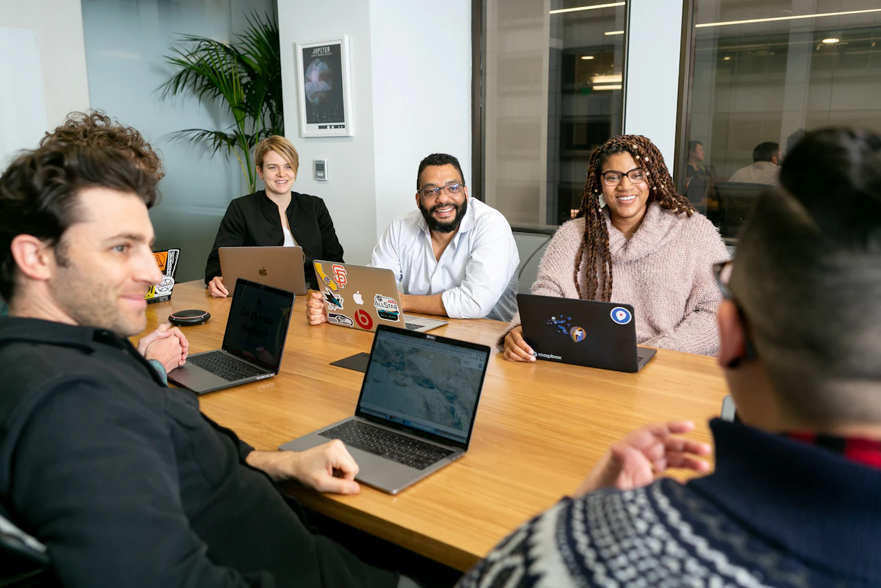 Equipo de una agencia colaborando alrededor de una mesa con portátiles